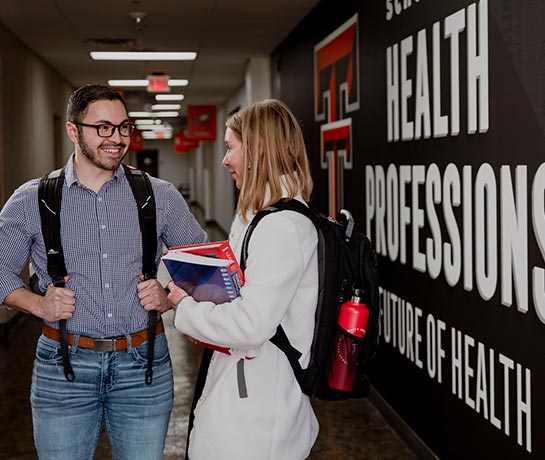 Two students with backpacks facing each other smiling Two students with backpacks facing each other smiling