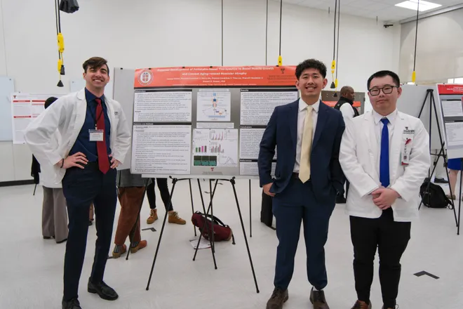 Three researchers posing in front of their research poster