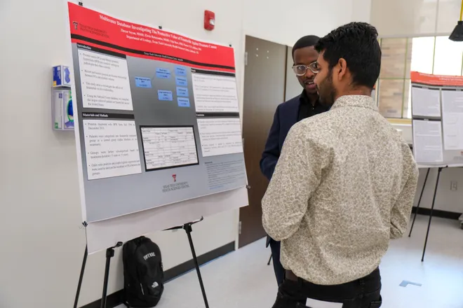 Two researchers discussing in front of research poster