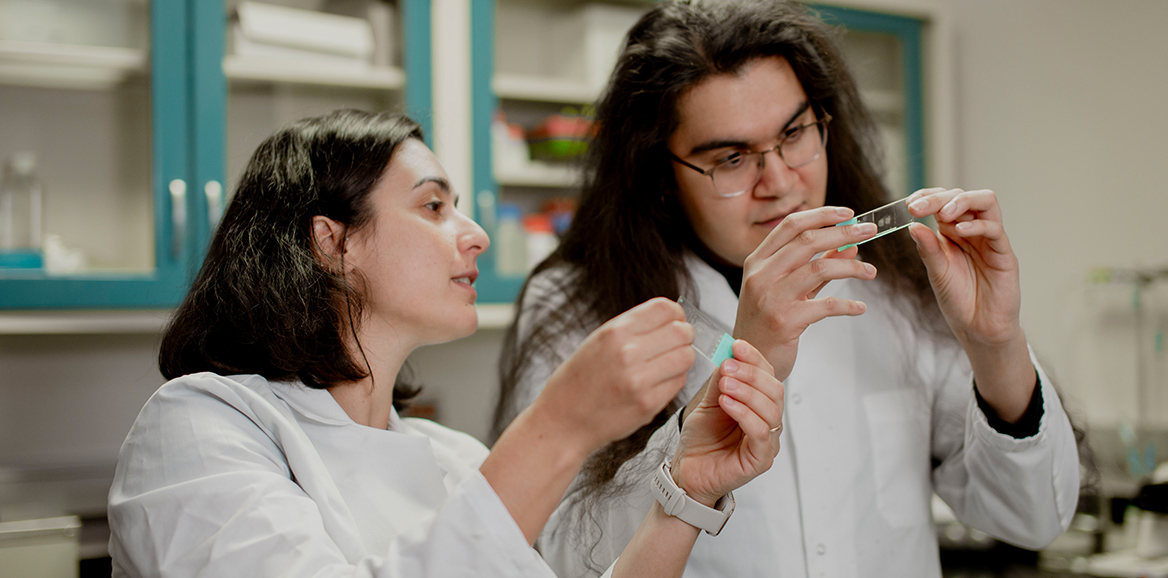 SOM students holding research equipment in the air looking at it.